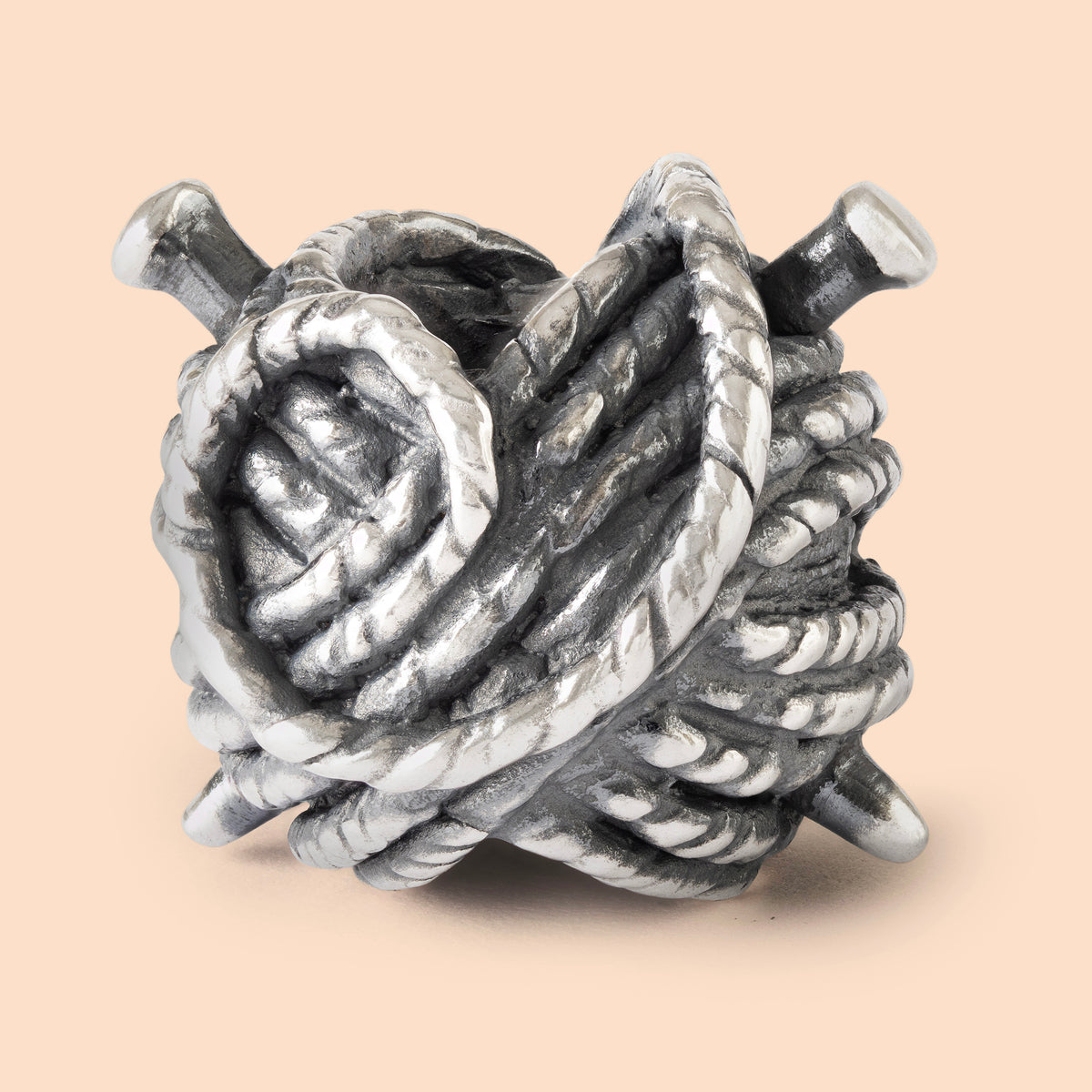 Silver knot charm with rope design on a beige background