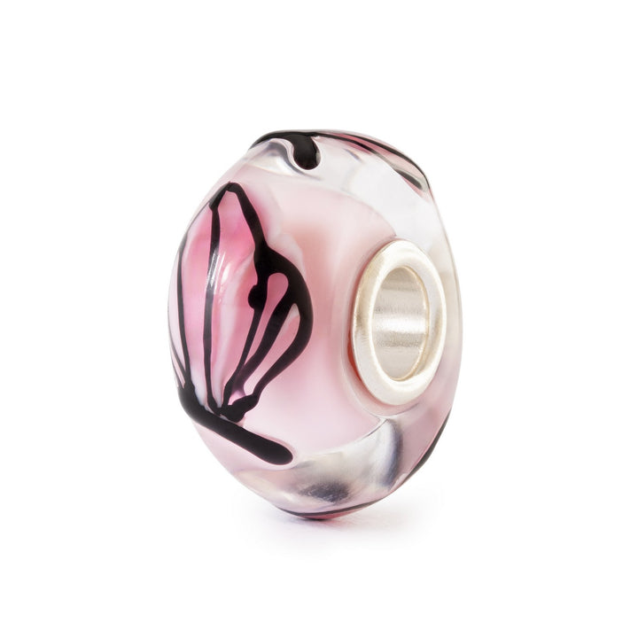 Glass charm bead with pink and black design on a white background