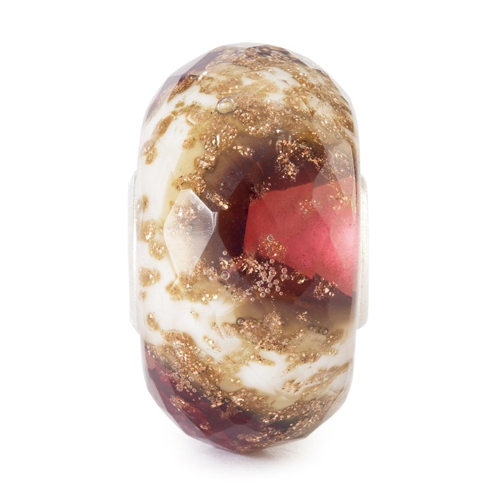 Glass bead with gold, red, and white colors on a white background