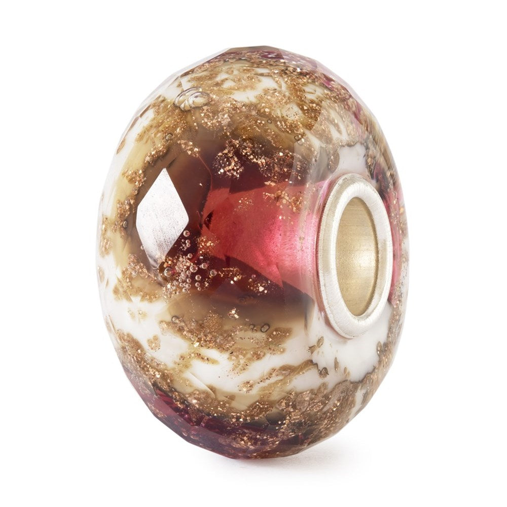 Glass bead with gold, red, and white colors on a white background