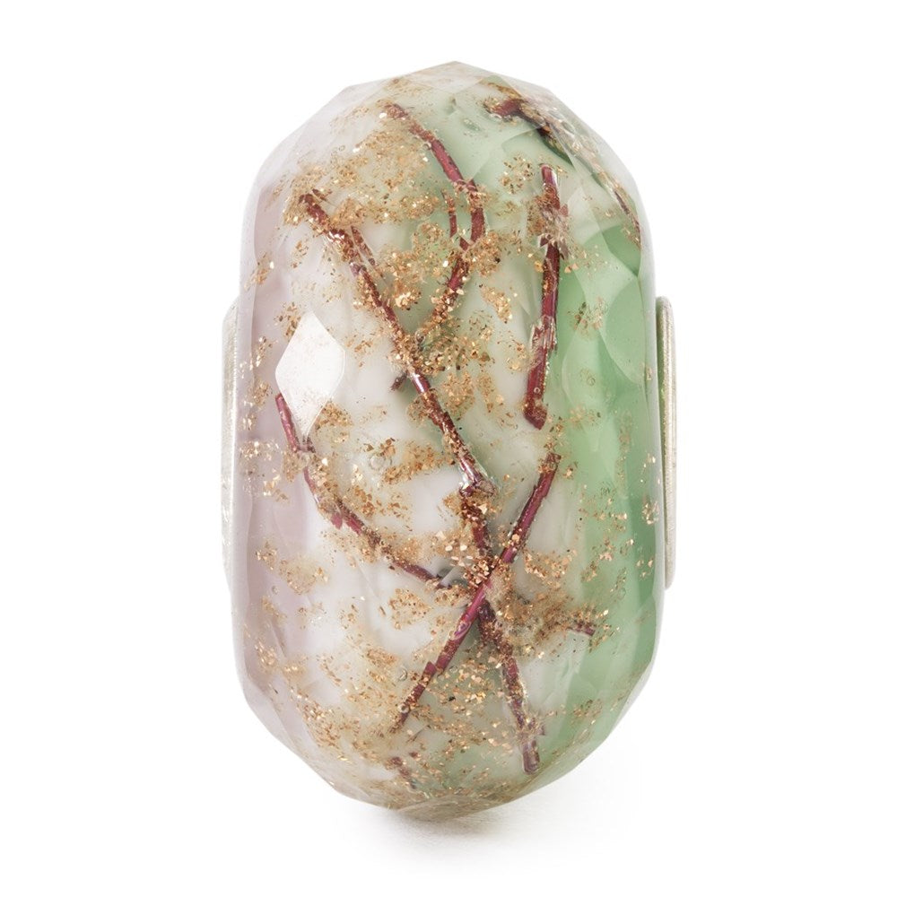 Decorative bead with green, white, and gold patterns on a white background