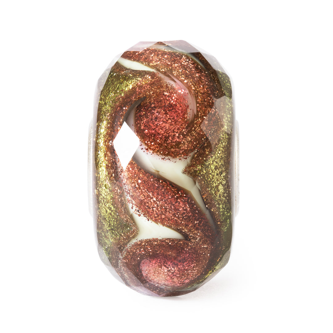 Decorative bead with gold, red, and white swirl pattern on a white background