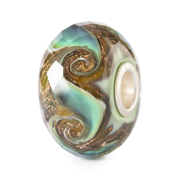 Decorative glass bead with swirling patterns on a white background