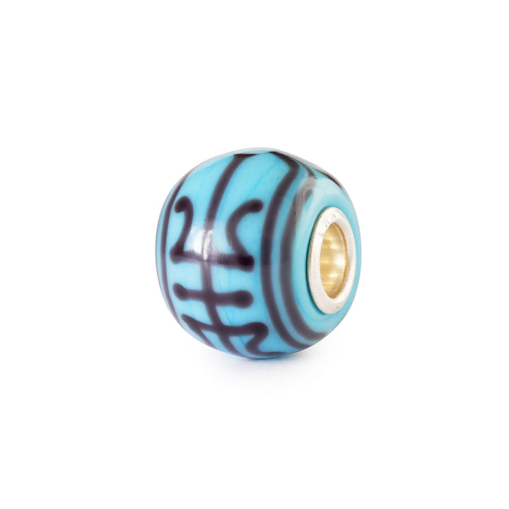 Blue glass bead with gold core on a white background