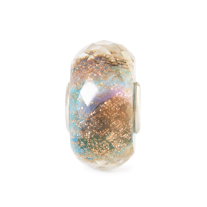 Decorative bead with gold and blue glitter on a white background