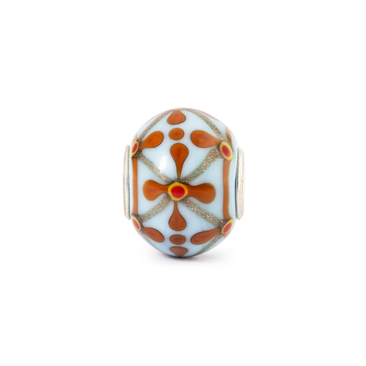 Decorative glass bead with brown and red patterns on a white background