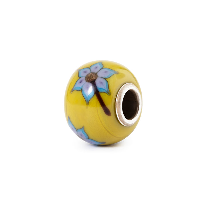 Yellow bead with floral design and silver accent on a white background