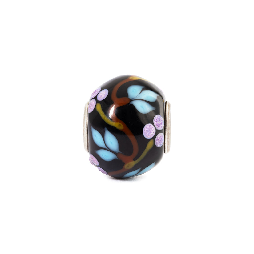 Decorative glass bead with floral patterns on a white background