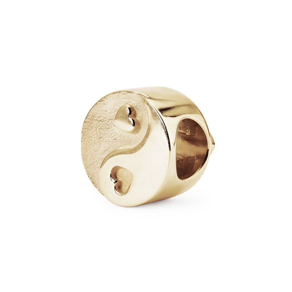 Gold charm with a yin yang design on a white background