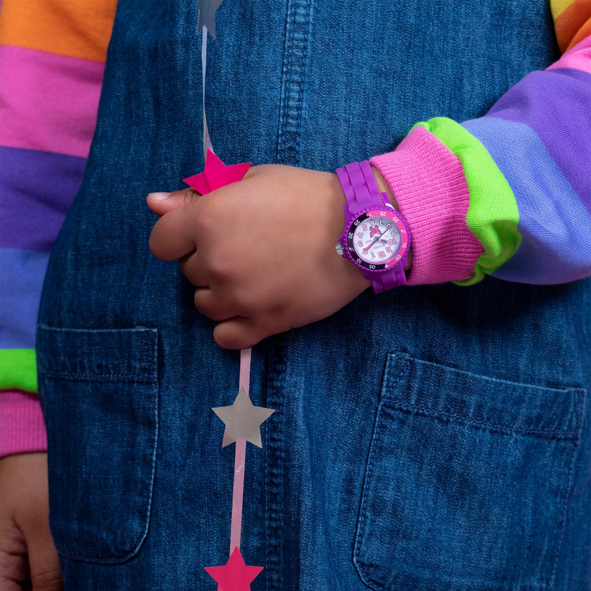 Person wearing a colorful jacket with a watch on a blue denim background