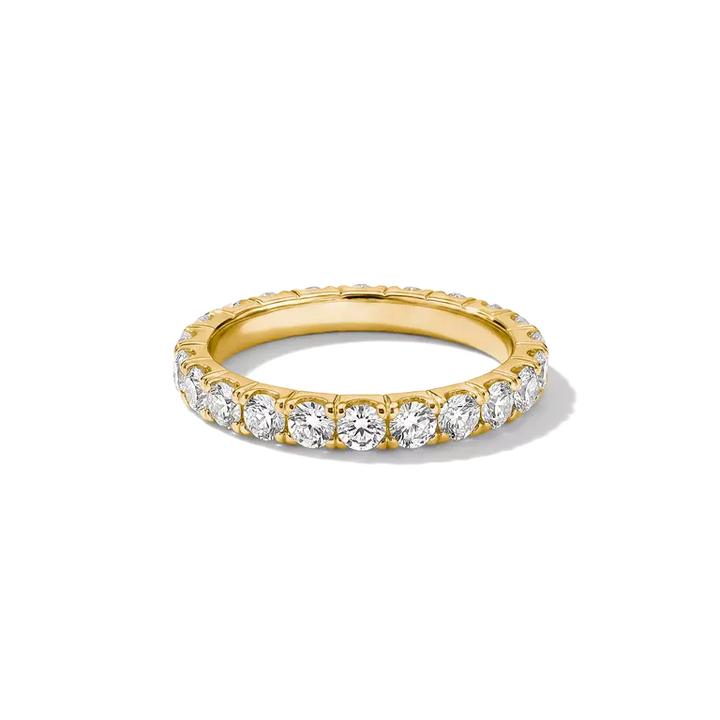 A yellow gold eternity ring set with round brilliant-cut diamonds, shown on a clean white background.