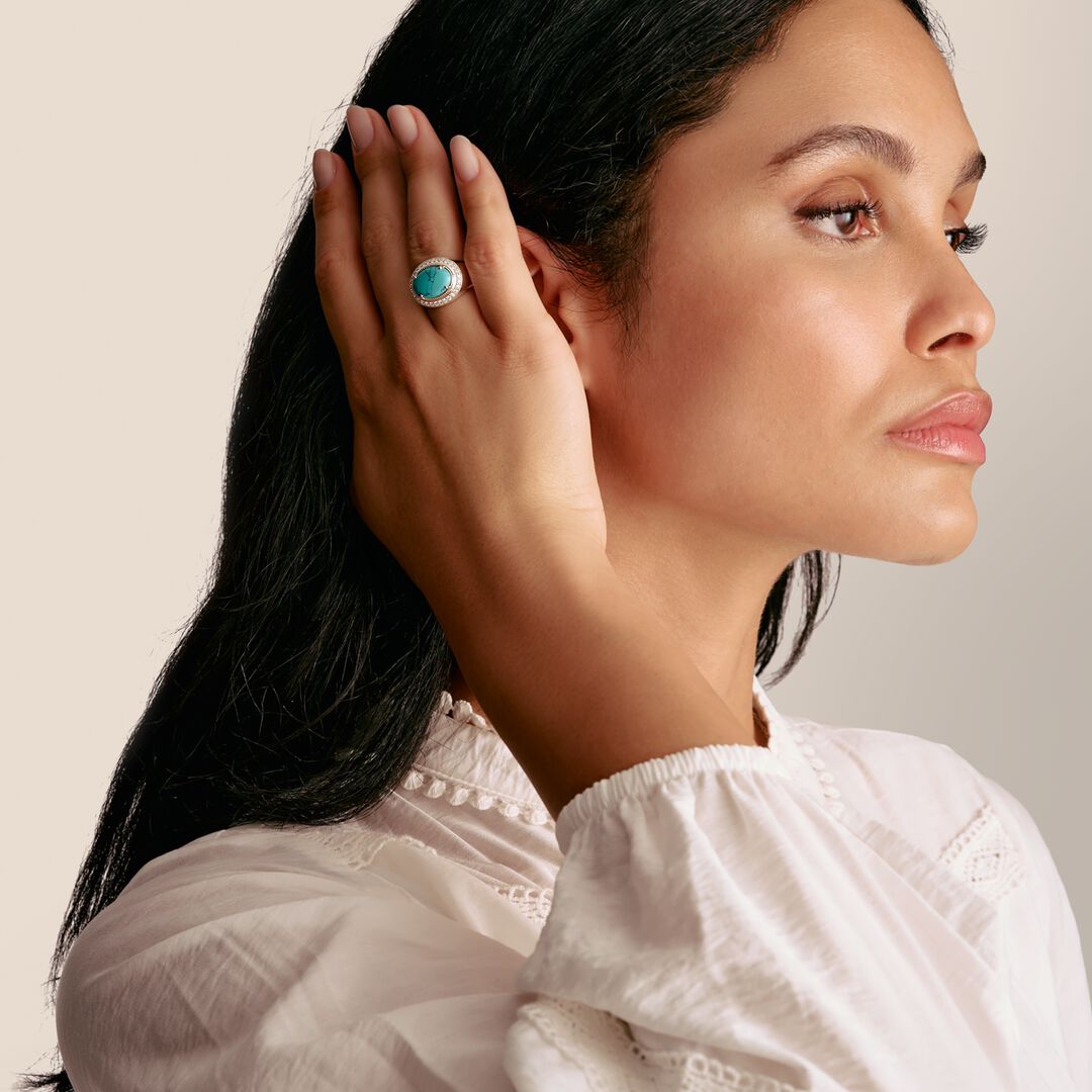Woman wearing a turquoise ring on her finger, with a neutral background