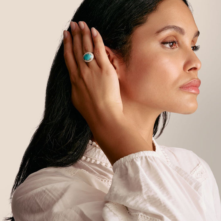 Woman wearing a turquoise ring on her finger, with a neutral background