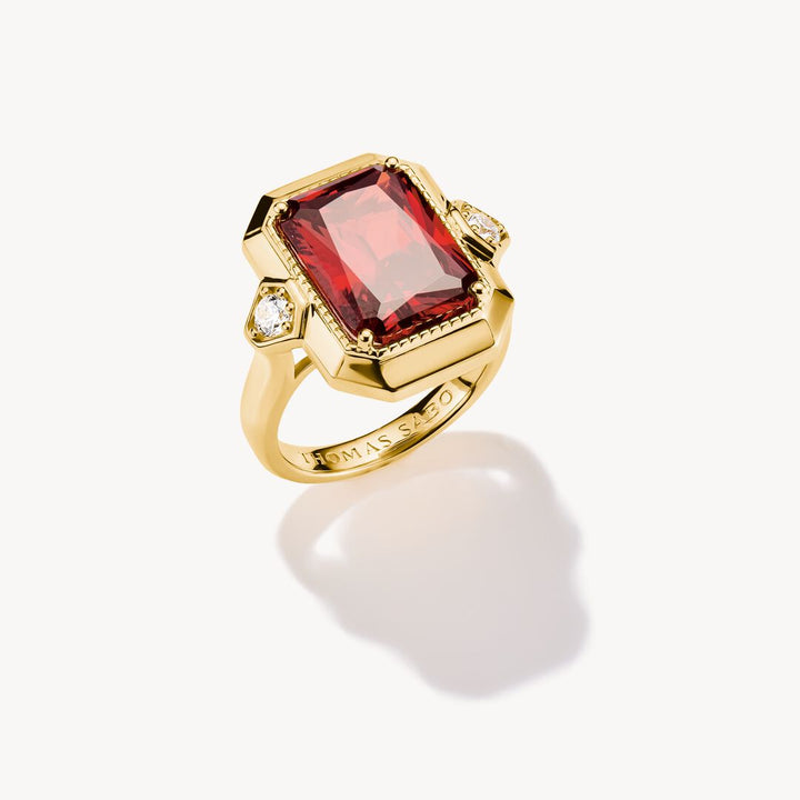 Gold ring with a red gemstone on a white background