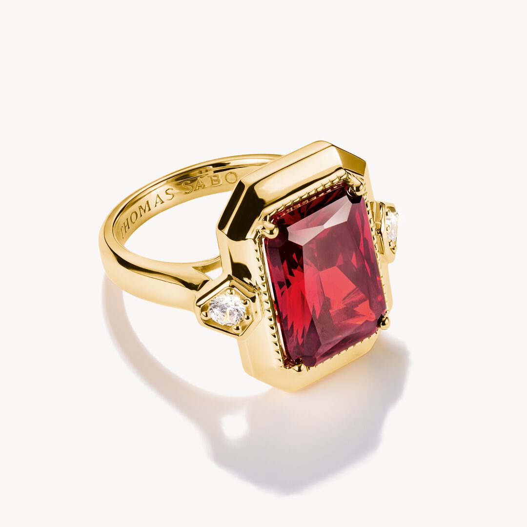 Gold ring with a red gemstone on a white background