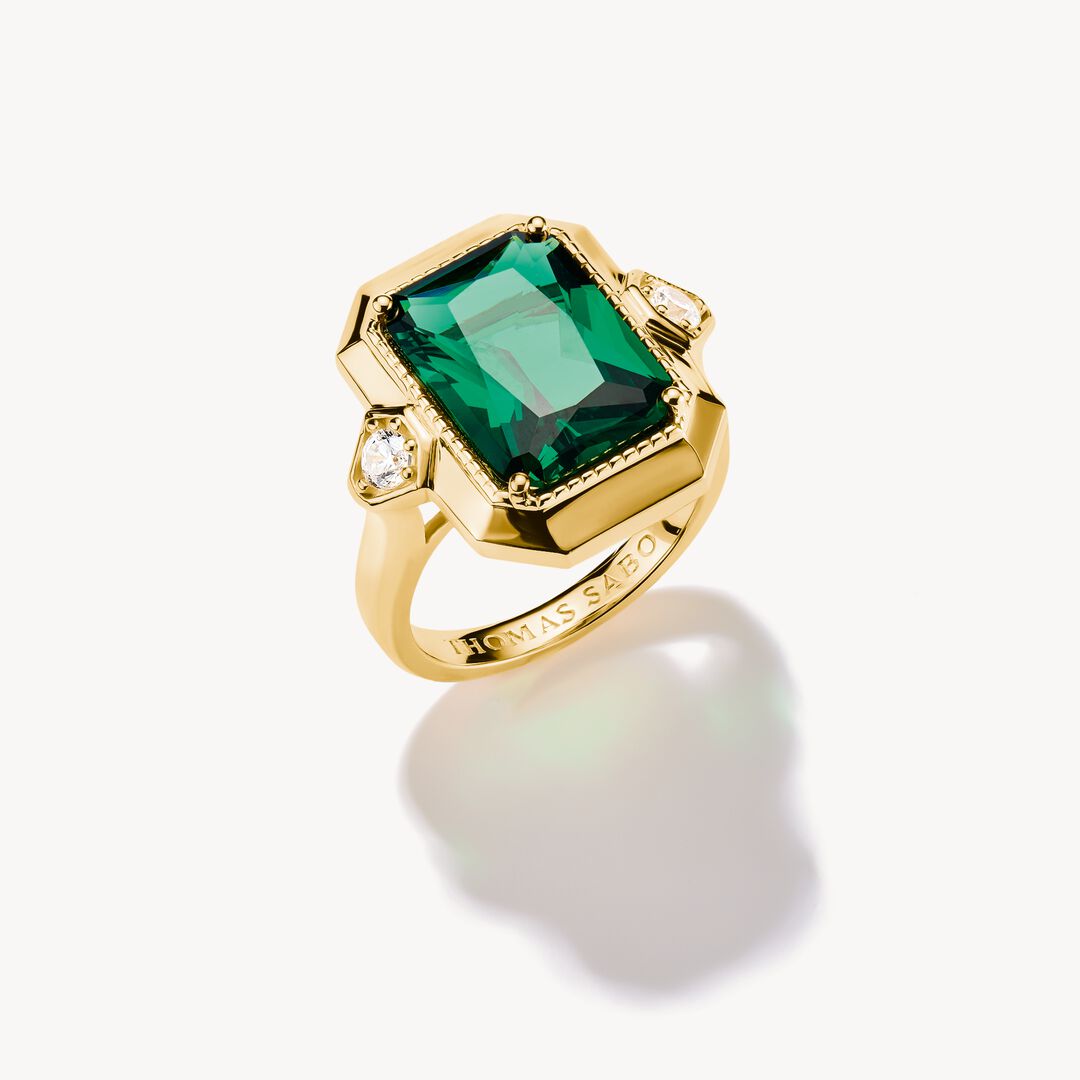 Gold ring with a green gemstone on a white background