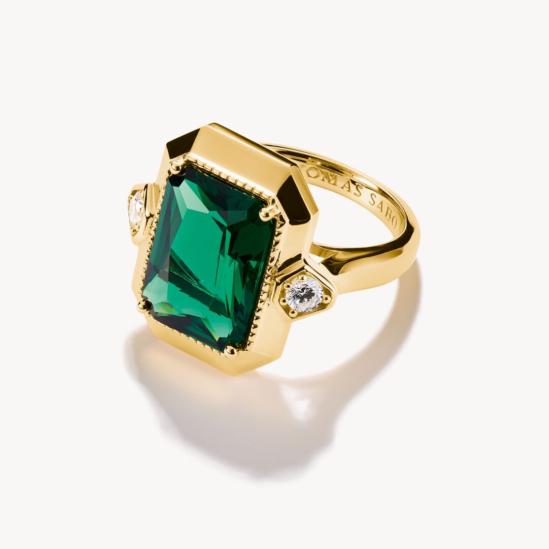 Gold ring with a green gemstone on a white background