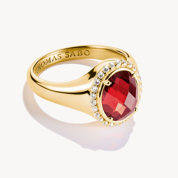 Gold ring with a red gemstone and 'THOMAS SABO' engraving on a white background