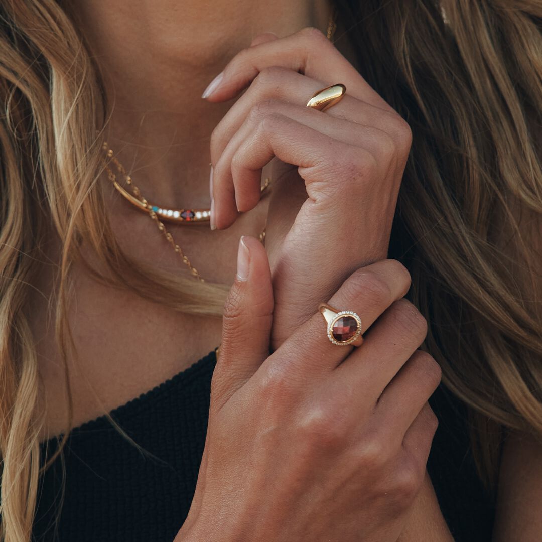 Close-up of a woman's hands wearing gold rings with gemstones.