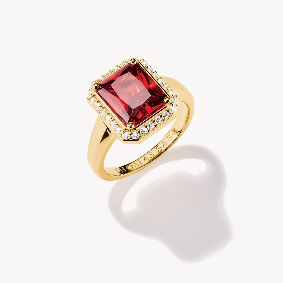 Gold ring with a red gemstone on a white background