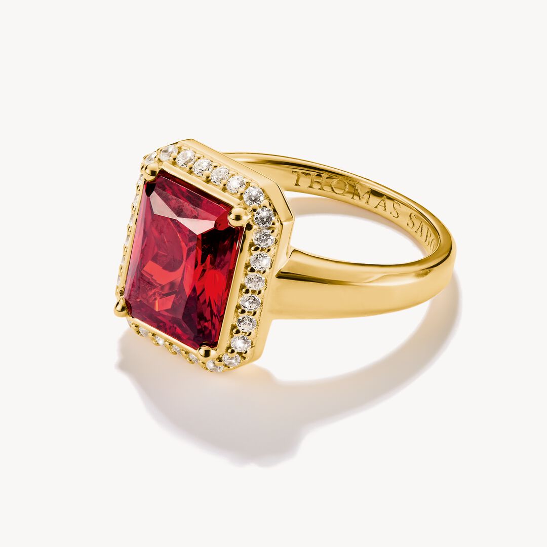 Gold ring with a red gemstone and diamonds on a white background