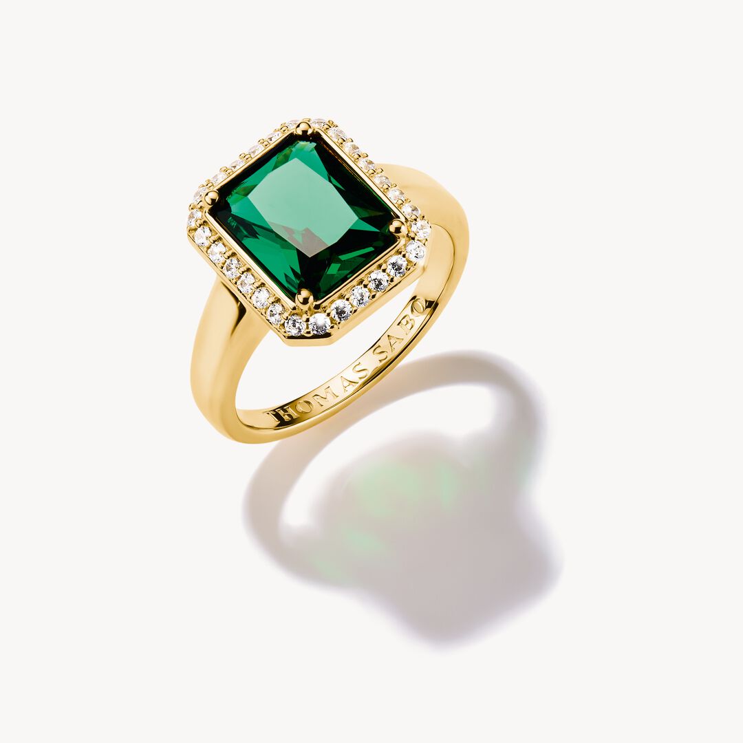 Gold ring with a green gemstone on a white background