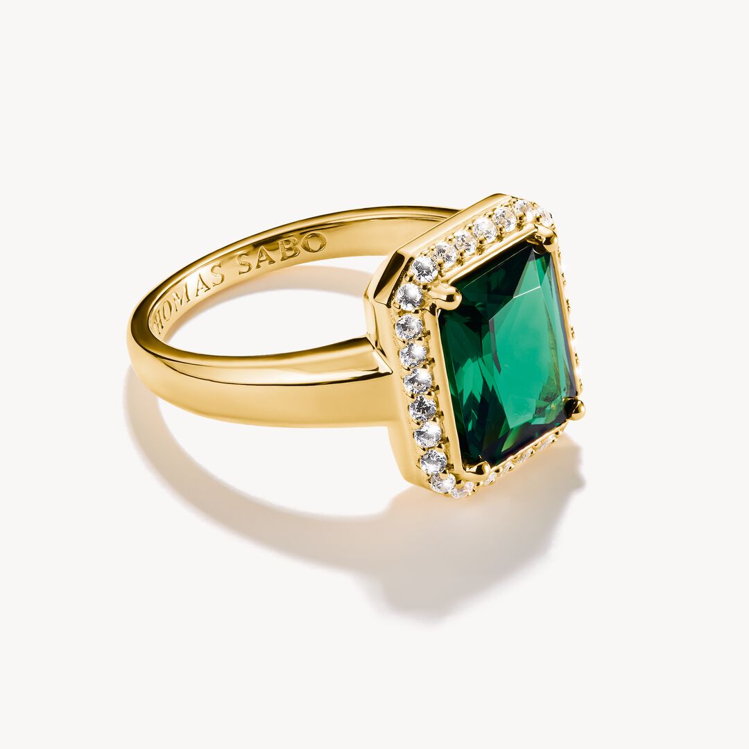 Gold ring with a green gemstone on a white background
