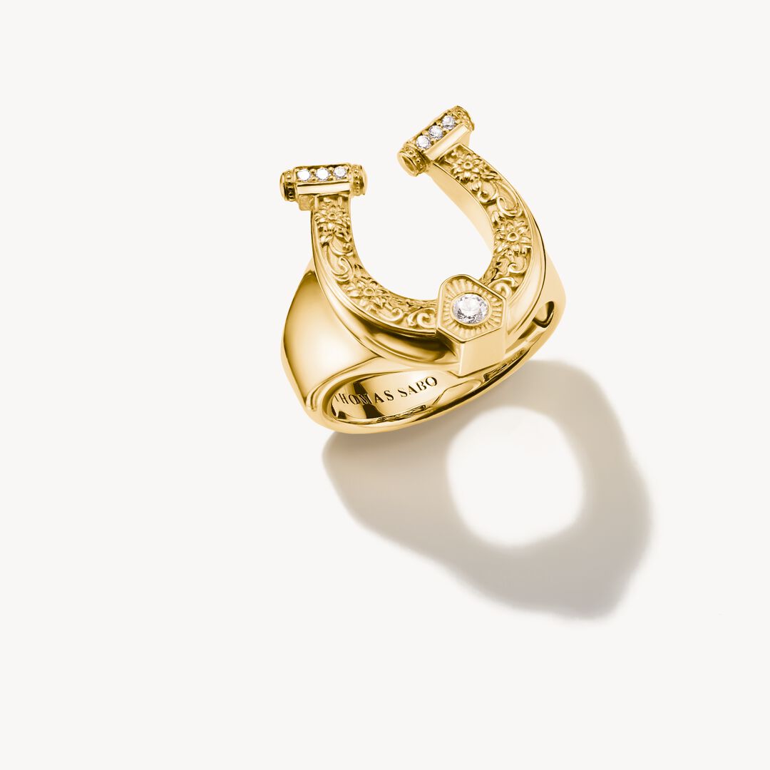 Gold horseshoe-shaped ring with diamonds on a white background