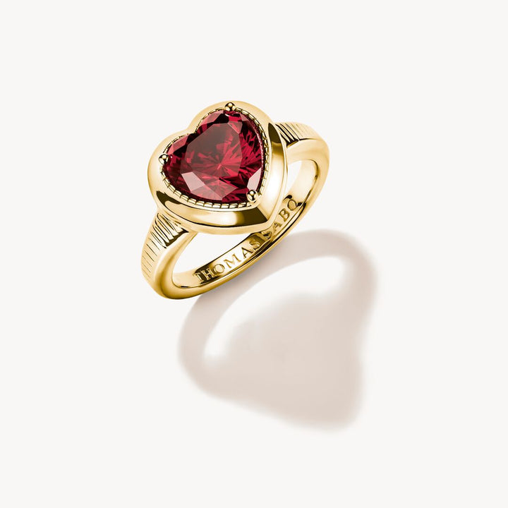 Gold ring with a red gemstone on a white background