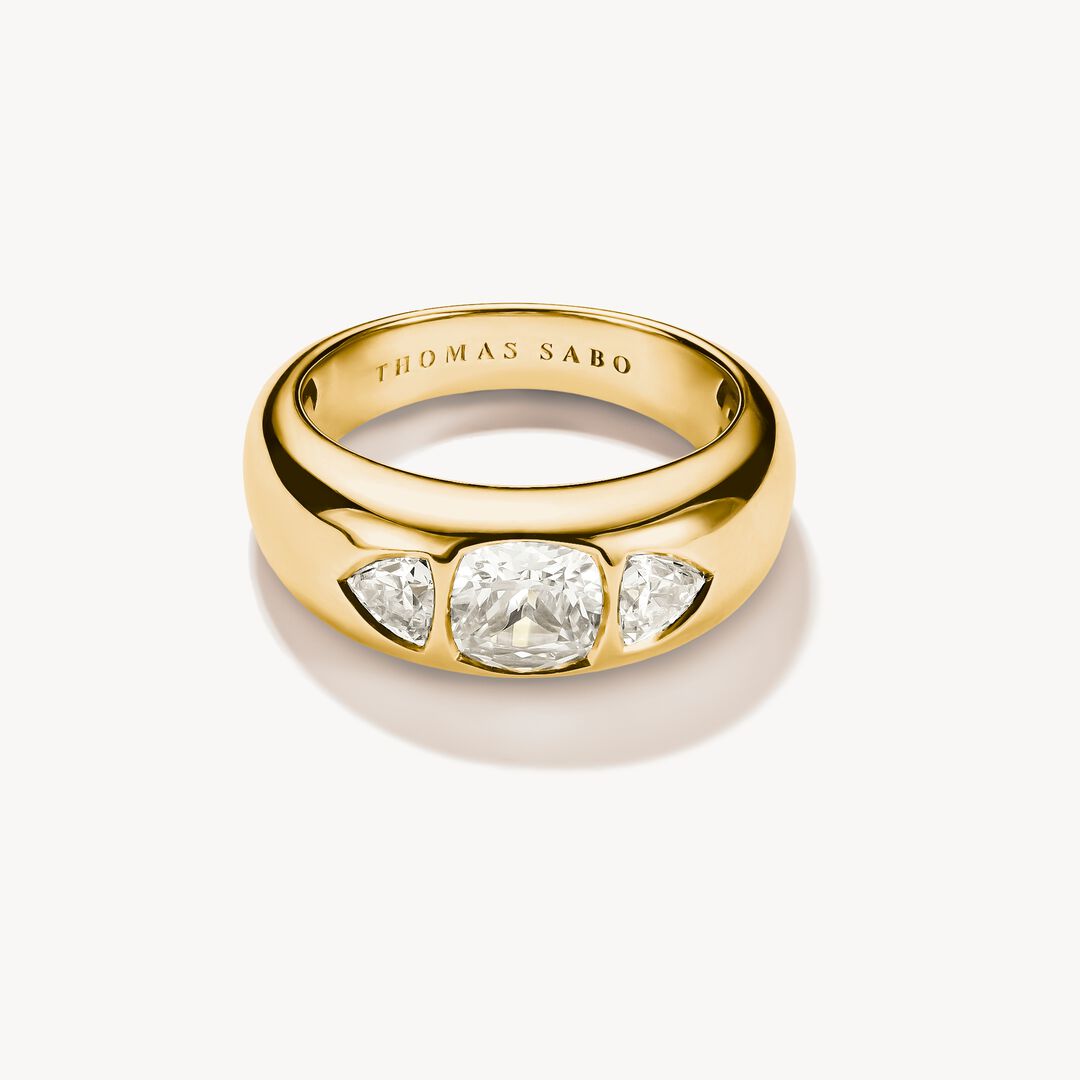 Gold ring with three clear gemstones on a white background, featuring the Thomas Sabo brand.