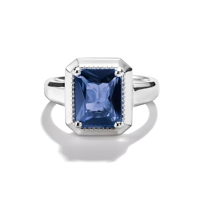 A Thomas Sabo ring featuring a rectangular cushion-cut blue sapphire gemstone in a silver-toned bezel setting with small pavé accents, shown on a white background with a soft reflection.