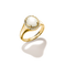A gold ring with a large oval white mother-of-pearl center stone, surrounded by a halo of small clear stones, shown on a white background with a soft shadow. The brand name 'THOMAS BATO' is engraved on the inner band.