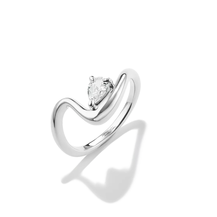 A silver-tone ring featuring a pear-cut clear gemstone in a prong setting, mounted on a sculptural curved band, shown on a white background with a soft shadow.