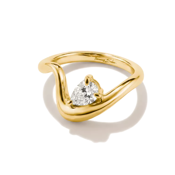 A yellow gold ring with a curved, wave-like band and a central triangular clear gemstone, shown on a white background with a soft shadow.