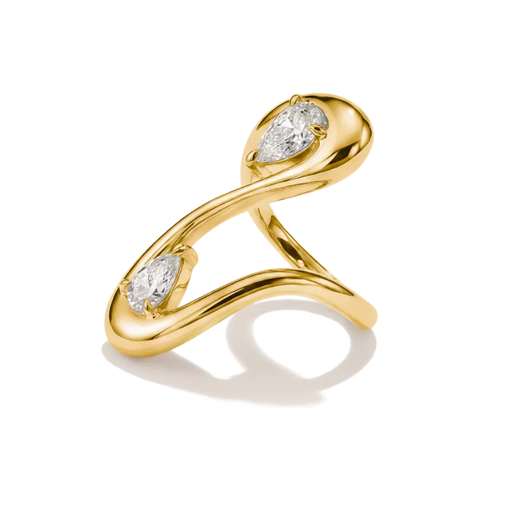 A yellow gold ring with an abstract, flowing infinity-like design featuring two pear-cut clear gemstones, shown on a white background with a soft shadow.