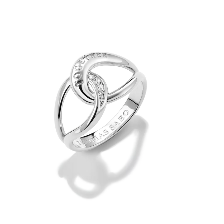 A silver ring by Thomas Sabo featuring interlocking curved bands with a small row of clear stones and the brand name 'THOMAS SABO' engraved on the band, set against a clean white background with a soft reflection.