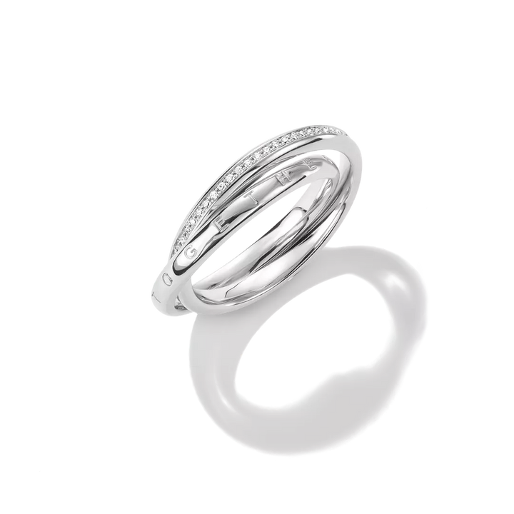 A polished silver-tone ring with a curved band featuring a row of small clear stones, photographed on a clean white background with a soft reflection below.