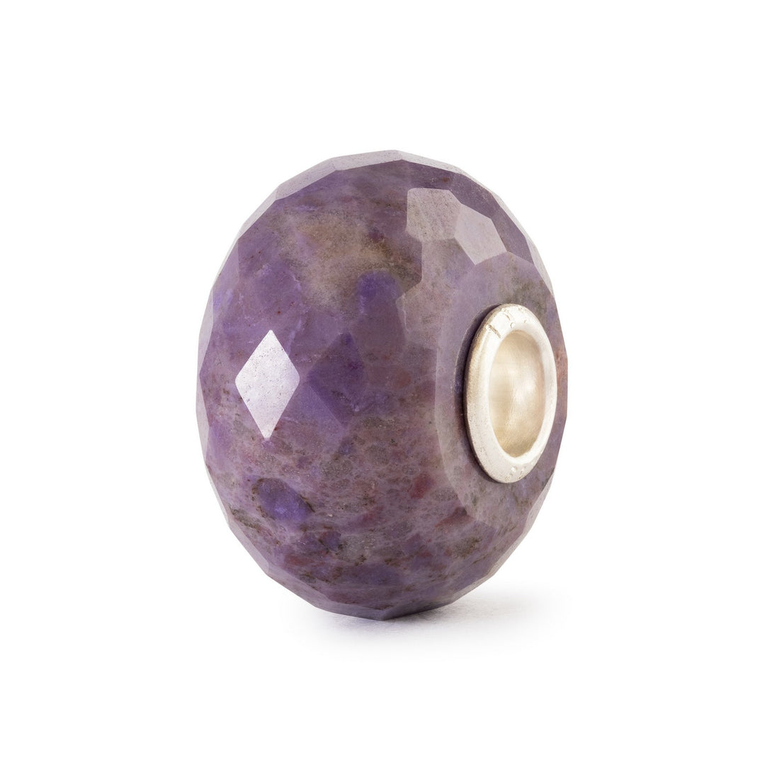 Faceted purple bead with a gold core on a white background