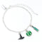 Silver bracelet with witch hat, green circle, and rectangular charm on a white background
