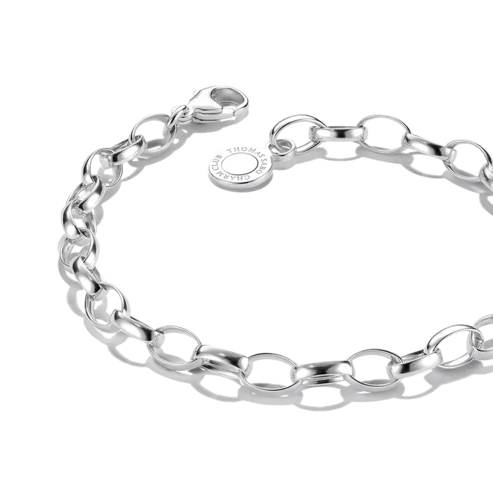 A polished silver chain bracelet with oval links and a lobster clasp, featuring a small round tag engraved with 'CRAFTED BY ST. HANSEN'.