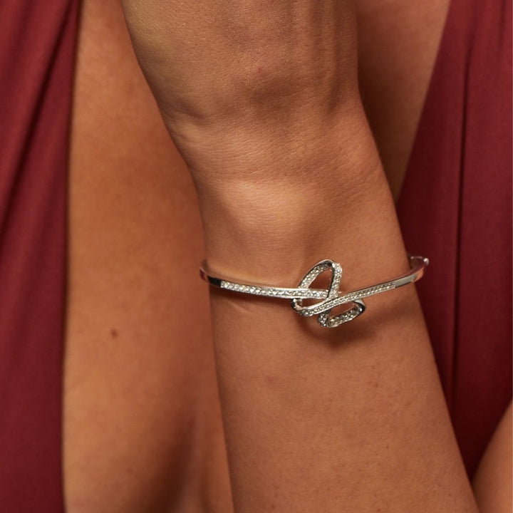 Silver bracelet on a wrist with a red fabric background