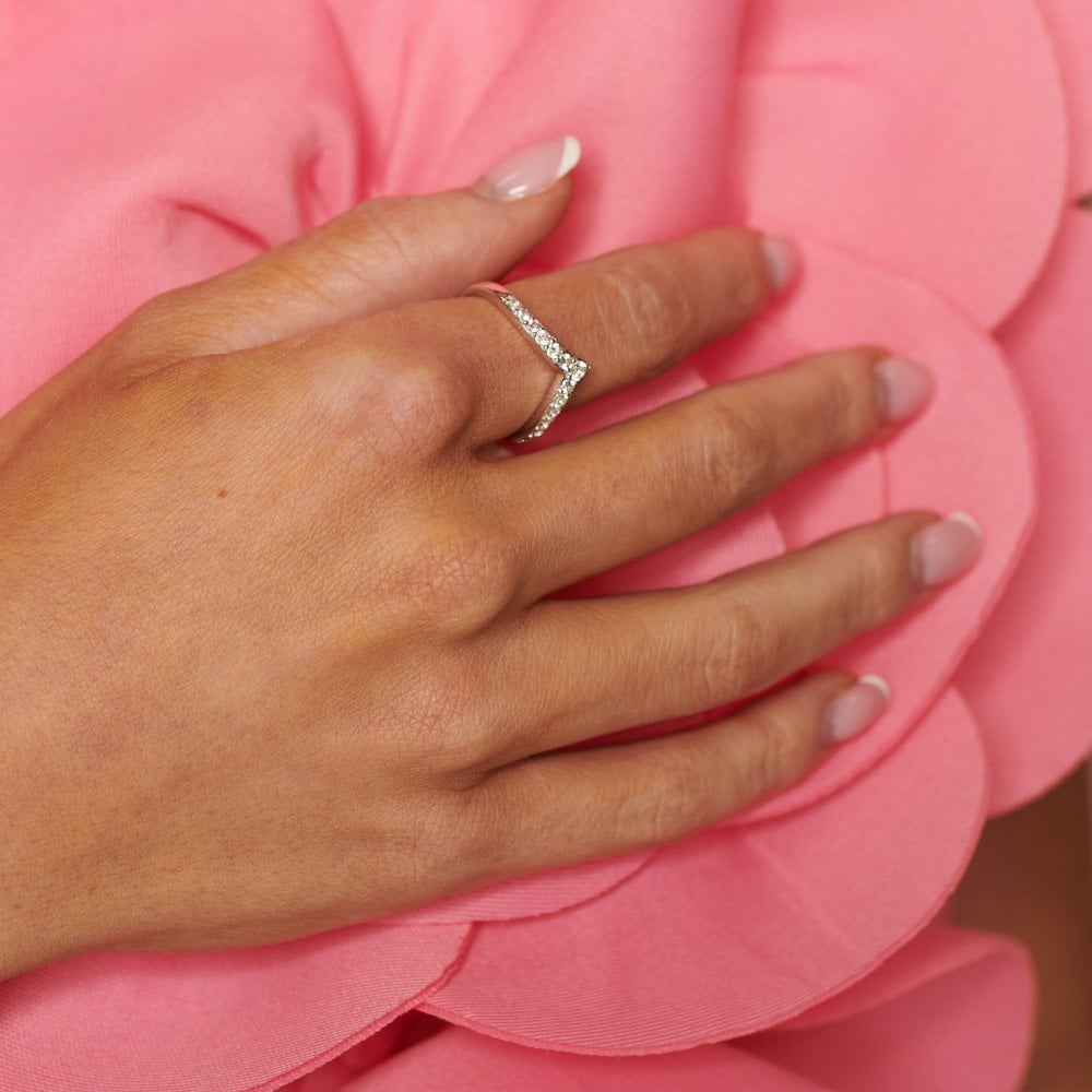 Hand wearing a silver ring on a pink floral background