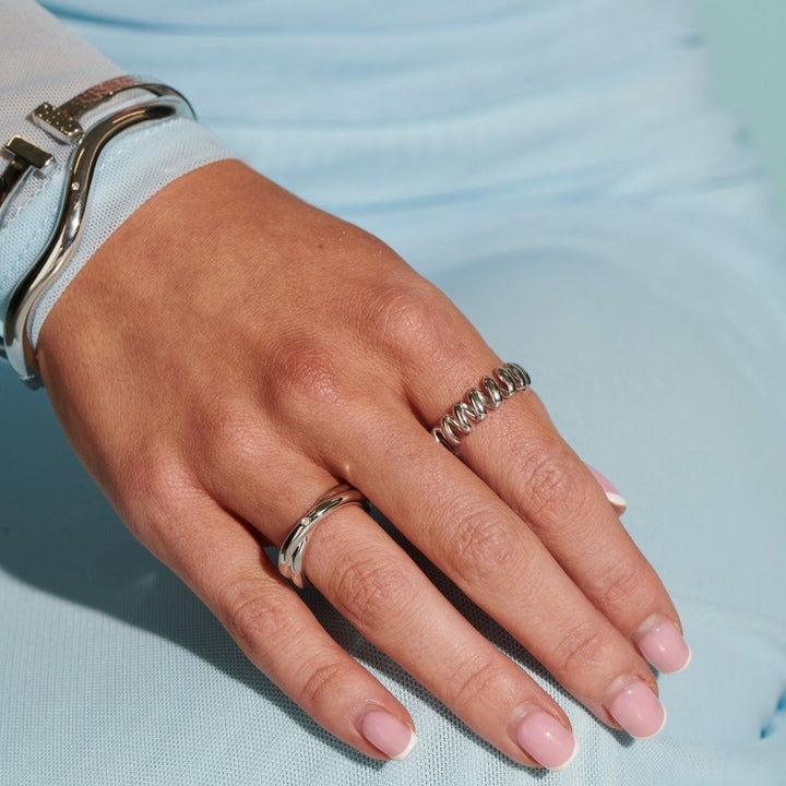 Hand with silver rings on a light blue background