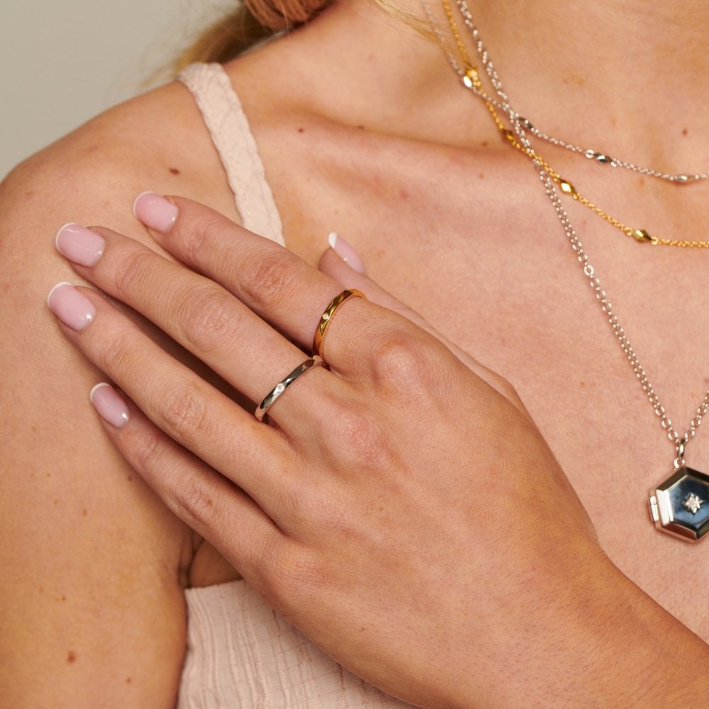 Close-up of a hand with gold rings on a blurred background