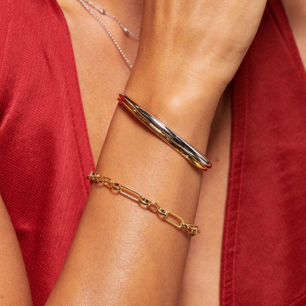 Gold bracelet on a wrist with a red garment in the background