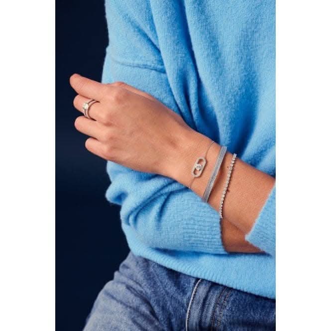 Chic close-up of a fashionably layered wrist adorned with a delicate bracelet featuring white zirconia, complemented by a vibrant blue sweater, showcasing contemporary elegance and sophistication.